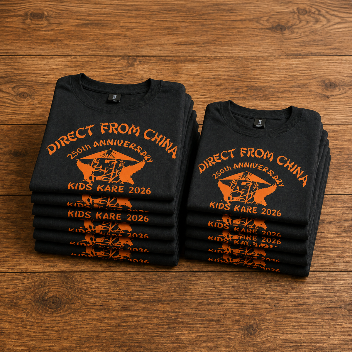 Two black t-shirts with orange text and graphics on a wooden surface